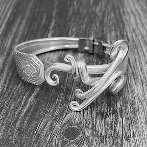May include: A silver bracelet made from a repurposed spoon, with a decorative swirl design.