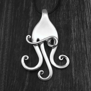 May include: A silver octopus pendant necklace made from a repurposed fork. The pendant is hanging from a black cord.