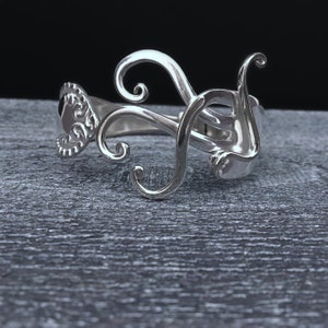 May include: Silver bracelet with a swirling, organic design. The bracelet is made of metal and has a polished finish.