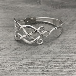 May include: Silver bracelet with a Celtic knot design. The bracelet is made from a repurposed spoon.