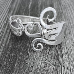 May include: A silver bracelet made from a repurposed fork, with the tines twisted into a decorative swirl design.