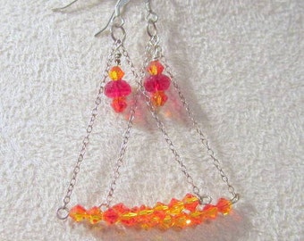 May include: Silver dangle earrings with a layered chain design. The earrings feature red and orange crystal beads.