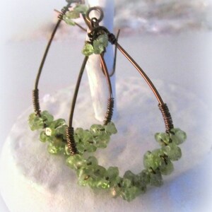 May include: A pair of teardrop-shaped earrings made with copper wire and green peridot stones.