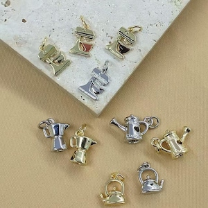 May include: A selection of miniature charms in gold and silver tones. The charms depict kitchen appliances such as stand mixers, coffee pots, teapots, and watering cans. These detailed charms are likely for jewellery or craft projects.