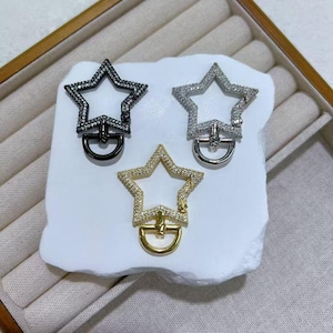 May include: Three star-shaped clasps with rhinestone embellishments. One is black with a black clasp, another is silver with a silver clasp, and the third is gold with a gold clasp. Each clasp has a D-ring for attachment.