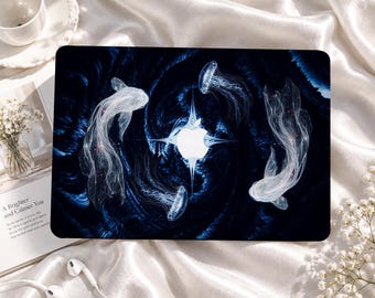 Könnte beinhalten: Eine Laptop-Hülle mit einem dunkelblauen, wirbelnden Hintergrund, zwei weißen, durchscheinenden Fischen und zwei Quallen, die ein zentrales weißes Apple-Logo umgeben. Das Design enthält ätherische, leuchtende Linien.