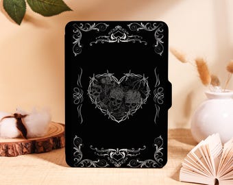 May include: Black tablet case featuring a heart-shaped design made of barbed wire, enclosing three skulls. The case has ornate silver scrollwork around the edges and a black background. The design is gothic and edgy.