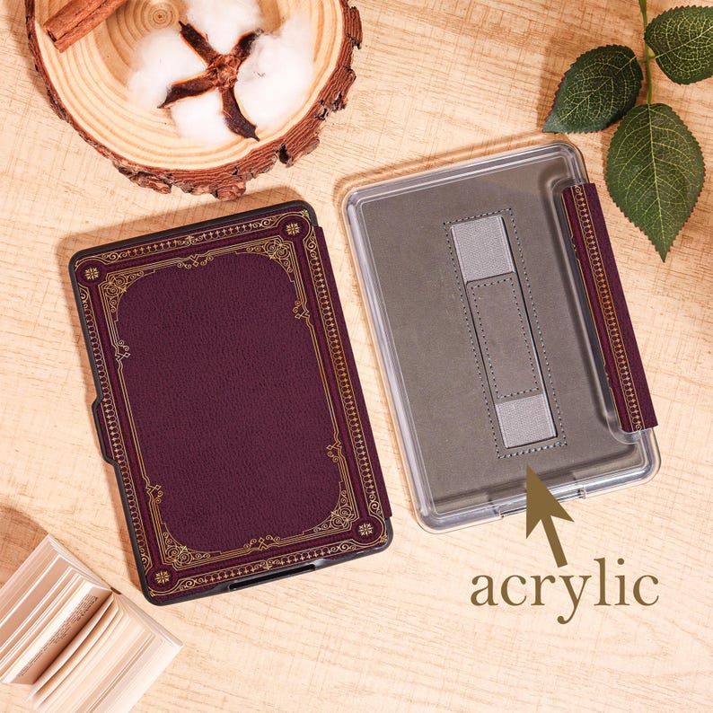 Puede incluir: Una funda burdeos para lector de libros electr&oacute;nicos con filigranas doradas y un soporte a juego. La funda est&aacute; abierta, revelando una parte trasera de acr&iacute;lico transparente. La palabra "acrylic" est&aacute; escrita en la funda. La funda est&aacute; dise&ntilde;ada para proteger un lector de libros electr&oacute;nicos.