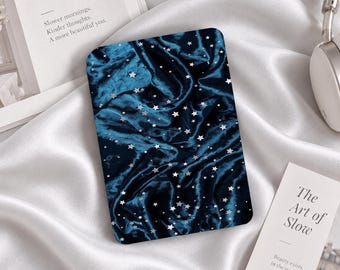 Könnte beinhalten: Eine rechteckige E-Reader-Hülle mit einer tief dunkelblauen Stofftextur und einem Muster aus kleinen, verstreuten silbernen Sternen. Die Oberfläche wirkt weich und drapiert, mit sichtbaren Falten und Glanzlichtern auf dem Stoff.