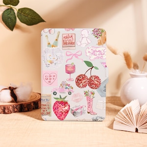 May include: A decorative case featuring a collage of pink and white illustrations. The design includes a disco ball, cherries, a cowboy boot, and text that reads "Match Made in Heaven" and "Today is going to be a good day".