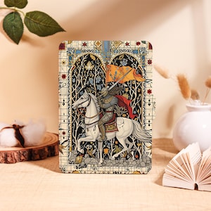 May include: A rectangular e-reader case featuring a detailed illustration of a knight in armor riding a white horse. The knight holds an orange flag and wears a red cape. The scene is framed by a stained glass window design with black, white, and gold accents.