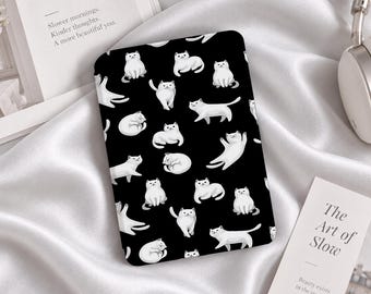 Könnte beinhalten: Eine rechteckige E-Reader-Hülle mit einem sich wiederholenden Muster aus weißen Katzen in verschiedenen Posen auf schwarzem Hintergrund. Die Katzen sind sitzend, sich streckend und zusammengerollt dargestellt, was ein dichtes, verspieltes Design ergibt.