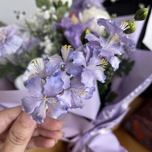 Hand holding a purple silk velvet flower hair fork with gold u-shaped pin. Handmade Ronghua crape myrtle design for updo hairstyles. Gradient violet petals made from mulberry silk.