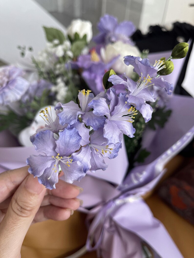 Hand holding a purple silk velvet flower hair fork with gold u-shaped pin. Handmade Ronghua crape myrtle design for updo hairstyles. Gradient violet petals made from mulberry silk.