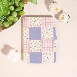 May include: A patchwork-style notebook cover with a mix of patterns. The design includes squares of pink plaid, blue polka dots, and floral prints in blue and pink. The cover has a curved edge on the right side.