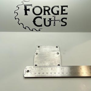 May include: Two silver metal plates with rounded corners and four holes each. The plates are stacked on top of each other. A ruler is placed below the plates, showing measurements in inches.