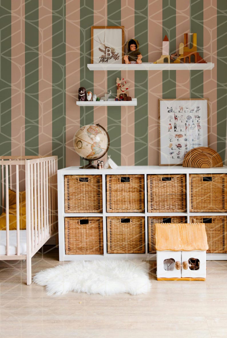 May include: A white crib with a yellow blanket, a white shelf with a globe, toys, and a framed alphabet chart, a white shelf with a framed picture and a doll, a white cabinet with wicker baskets, and a white rug in front of a green and pink striped wallpaper.