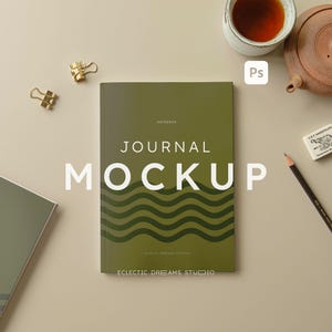 Puede incluir: Una maqueta de diario verde con el texto "JOURNAL MOCKUP" en blanco. El diario tiene un patrón ondulado y el texto "ECLECTIC DREAMS STUDIO" en la parte inferior.