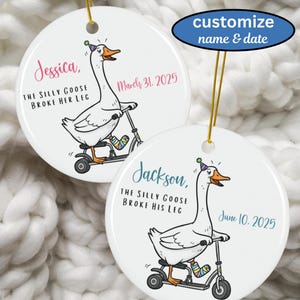 May include: Two white ceramic ornaments with gold hanging cords. Each features a cartoon goose riding a scooter with a broken leg. One says "Jessica" and "March 31, 2025", the other says "Jackson" and "June 10, 2025". Text above says "customize name & date".