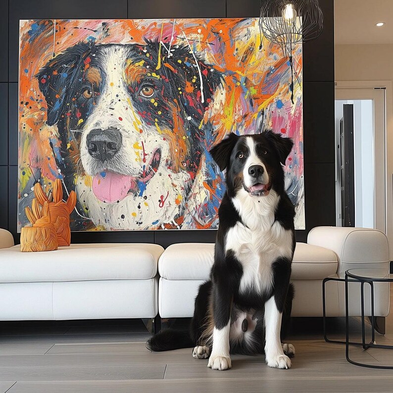 May include: A black and white dog sits in front of a large, colourful abstract painting of a dog's face. The painting features vibrant splashes of orange, pink, yellow, and blue. A white sofa and decorative orange sculpture are also in the image.