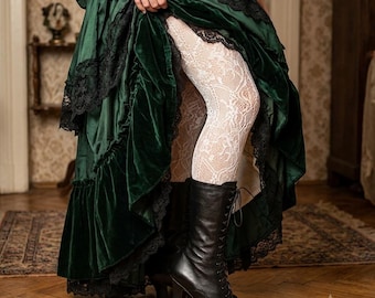 May include: A dark green velvet skirt with black lace trim, worn over white floral lace tights and paired with black leather lace-up boots featuring a mid-height heel. The skirt has a layered, ruffled hemline and a voluminous, gathered silhouette.