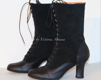 May include: A pair of black mid-calf boots featuring a lace-up front closure with black laces, a smooth leather toe and heel cap, and a suede-like shaft. The boots have a block heel and include the text by Victoria Adriana on the side.