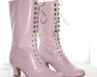 May include: A pair of light pink leather lace-up boots with a low heel. The boots have a pointed toe and a decorative buckle on the laces.