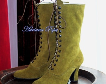 May include: A pair of olive green suede boots with lace-up fronts and a chunky heel. The boots have a brown lace and black eyelets.