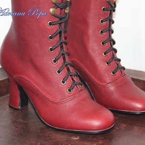 May include: A pair of burgundy leather ankle boots with black laces and gold eyelets. The boots have a high heel and a pointed toe.