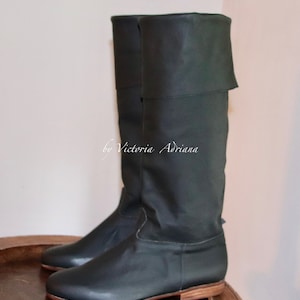 May include: A pair of dark green leather knee-high boots with a fold-over cuff. The boots have a rounded toe and a low block heel.