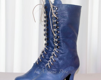 May include: A pair of blue leather boots with a lace-up design. The boots have a mid-calf height, a rounded toe, and a small heel. The laces are white, and the eyelets are silver. The boots are set against a white background.