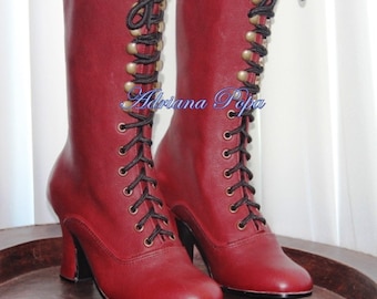 May include: A pair of burgundy leather lace-up boots with black laces and gold-toned eyelets. The boots have a high heel and a rounded toe.