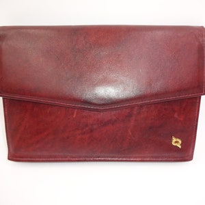 May include: A burgundy leather clutch with a gold logo.