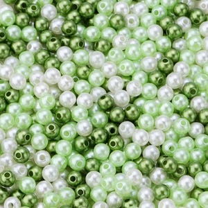 May include: A collection of small, round beads in shades of green and white. The beads have a glossy finish and are scattered, creating a textured surface. The color palette includes light green, dark green, and white.