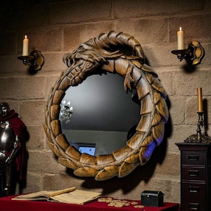 Puede incluir: Espejo redondo de madera con marco de dragón. El marco tallado representa un dragón comiéndose su propia cola, con detalles dorados. Dos candelabros flanquean el espejo en una pared de ladrillo.