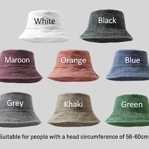 Op de afbeelding: Acht emmerhoeden in verschillende kleuren: wit, zwart, bordeaux, oranje, blauw, grijs, kaki en groen. Elke hoed is gelabeld met zijn kleur. De tekst geeft aan dat de hoeden geschikt zijn voor hoofdomtrekken van 56-60cm.