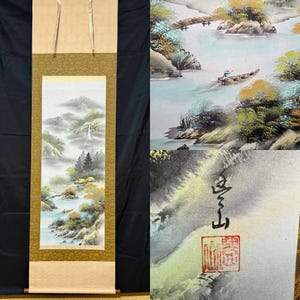 May include: A traditional Japanese scroll painting depicting a serene landscape with mountains, a waterfall, and a river. The artwork features muted colors and a sense of depth, with a small boat on the water. The scroll is framed in gold and tan.