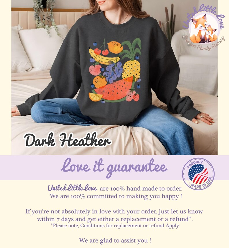 May include: Dark heather sweatshirt featuring a colorful fruit illustration. The design includes a pineapple, watermelon, grapes, strawberries, and other fruits. The text "love it guarantee" is below the sweatshirt.