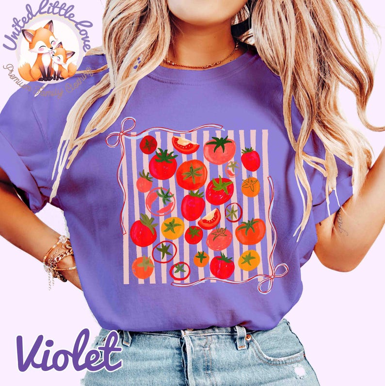 Peut inclure: T-shirt violet avec un motif de tomates. Le motif pr&eacute;sente des tomates rouges, oranges et jaunes sur un fond ray&eacute;. Le t-shirt a des manches courtes et un col rond. Le texte "Violet" est en bas du t-shirt.