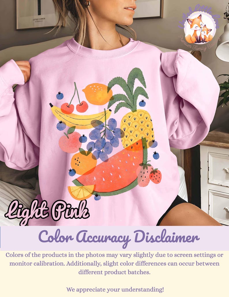 May include: Light pink sweatshirt featuring a colorful fruit graphic. The design includes a banana, cherries, grapes, orange, pineapple, watermelon, and strawberries. The words "light pink" are written in cursive on the bottom left.