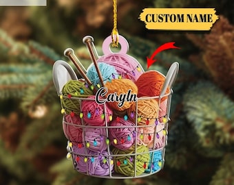 May include: A 2D flat ornament shaped like a wire basket filled with colorful yarn balls and knitting needles. The ornament has the text "Caryn" and "Custom Name" on it, and is decorated with string lights. The text "2D FLAT" is also visible.