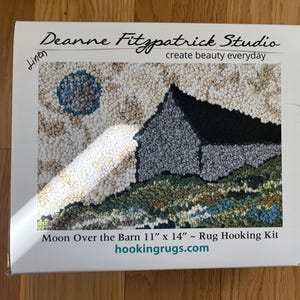 May include: A rug hooking kit box featuring a landscape scene with a barn under a moon. The kit is titled "Moon Over the Barn" and measures 11" x 14". The box has the text "Deanne Fitzpatrick Studio" and "create beauty everyday".