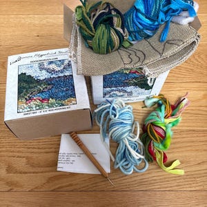 May include: A Sweet Bay rug hooking kit with a box, yarn, and a hook. The kit includes a printed canvas, various colors of yarn in shades of blue, green, and other colors. The box has the text "Sweet Bay - 6" x 6" Rug Hooking Kit".