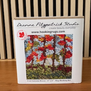 May include: A boxed rug hooking kit titled "Cool Autumn Breeze" by Deanne Fitzpatrick Studio. The kit features a colorful, textured design of autumn trees. The rug measures 6 x 6 inches.