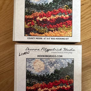 May include: Two boxes of rug hooking kits. The kits feature a colorful landscape design with a moon, sky, and fields of red, orange, and green. The text "COUNTY MOON - 6" X 6" RUG HOOKING KIT" is visible. The brand name is "HOOKINGRUGS.COM".