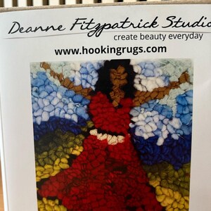 May include: A rug hooking kit featuring a colorful design of a woman in a red dress with outstretched arms. The kit includes the text "Joy - 6" x 6" - Rug Hooking Kit" and the website www.hookingrugs.com.