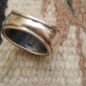 May include: A silver ring with a smooth, rounded surface. The inside of the band is stamped with the text "925".