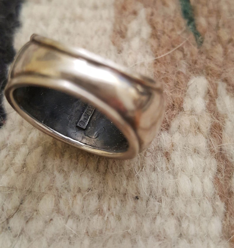 May include: A silver ring with a smooth, rounded surface. The inside of the band is stamped with the text "925".