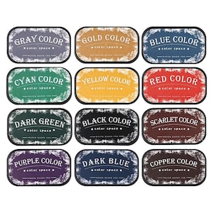 May include: A collection of twelve ink pads in various colors, including gray, gold, blue, cyan, yellow, red, dark green, black, scarlet, purple, dark blue, and copper. Each pad has a rectangular shape with rounded corners and text that reads "color space".