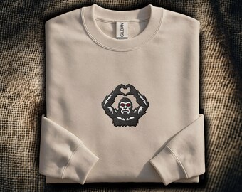 Sudadera bordada con manos de Bigfoot en forma de corazón: Divertido gesto de Sasquatch con las manos en forma de corazón | Cuello redondo de críptido | Bordado de silueta de Bigfoot
